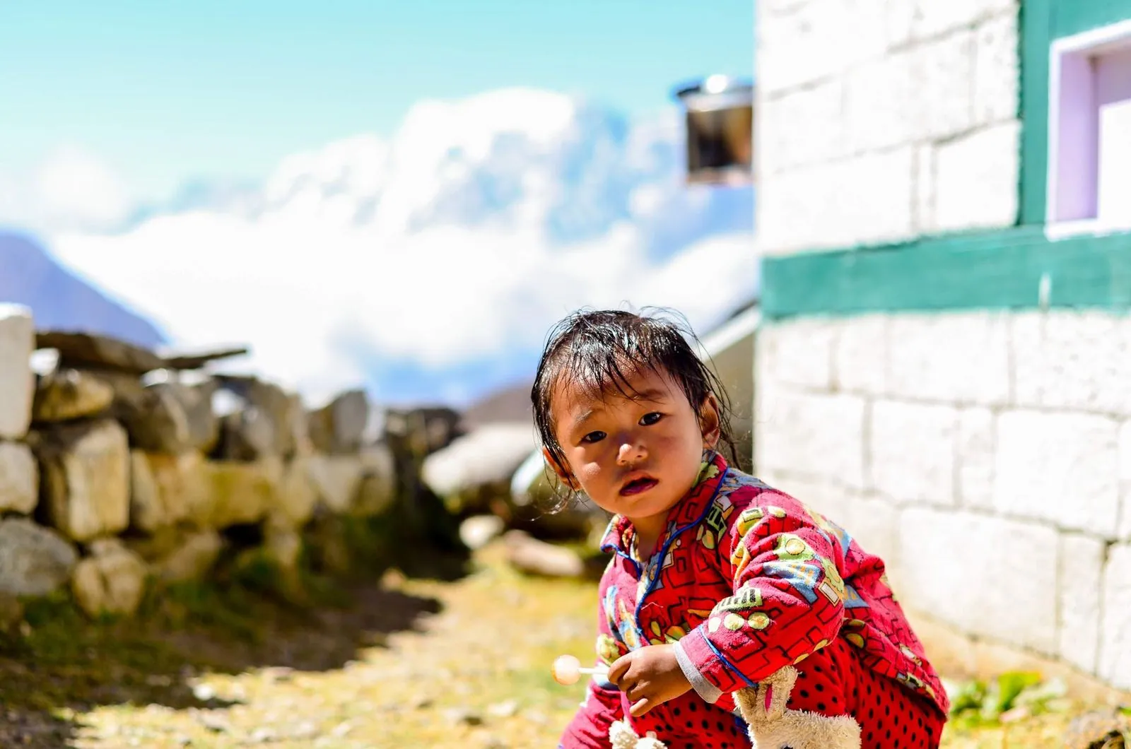 Un niño en una aldea del valle del Khumbu, junto a una casa de piedra encalada.