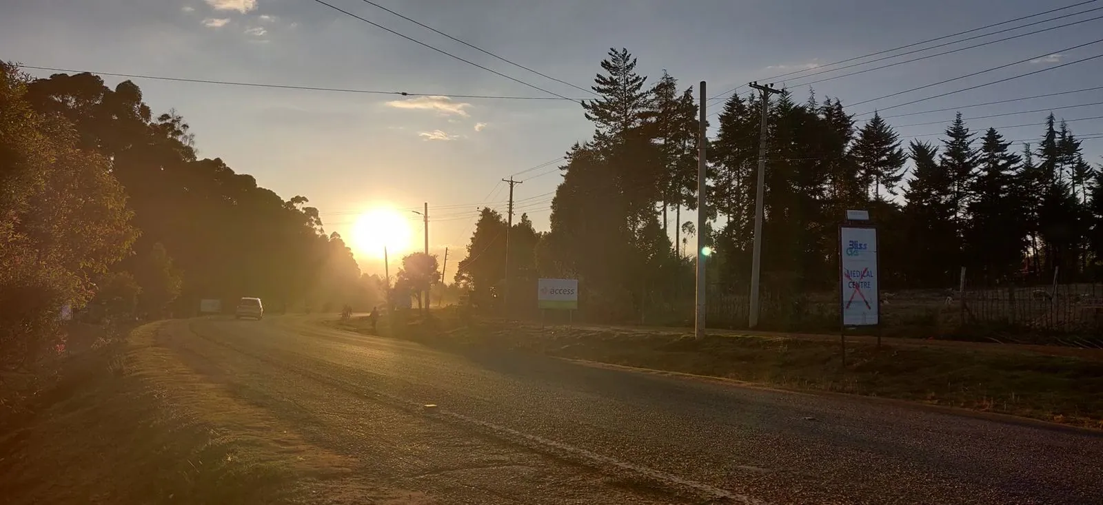 Atardecer en una carretera bordeada de pinos, cerca de Iten.